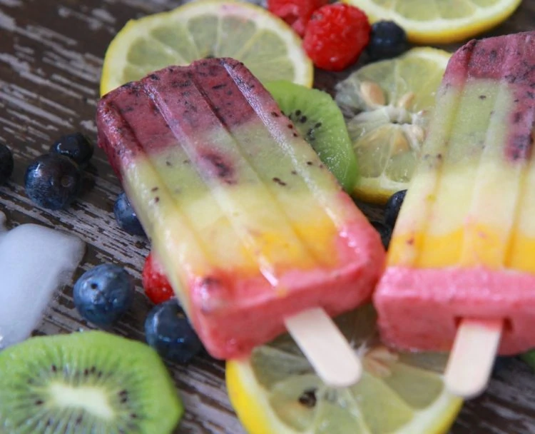 Rainbow Smoothie Popsicles on the table with kiwi's and lemon slices.