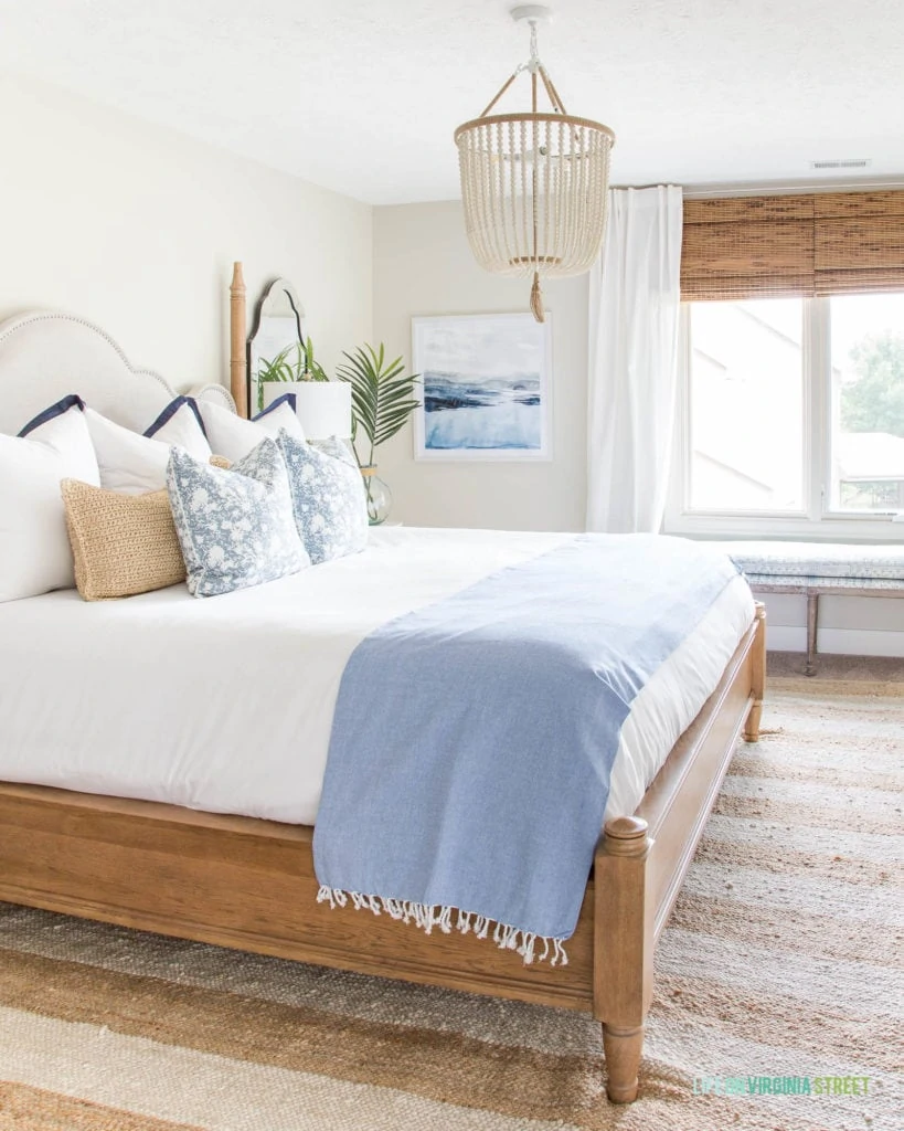Summer guest bedroom updates with blue and white decor and natural wood tones. Love the white bead chandelier paired with the beachy watercolor artwork.