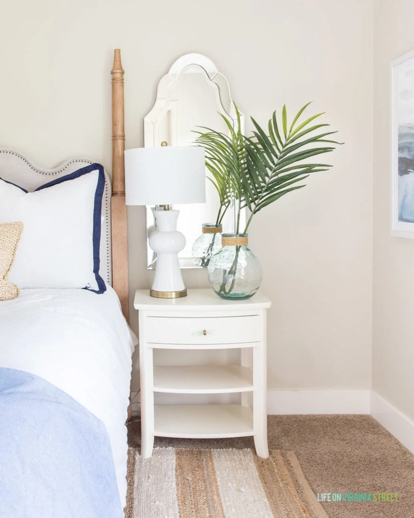 A white side table beside the bed in the guest bedroom.