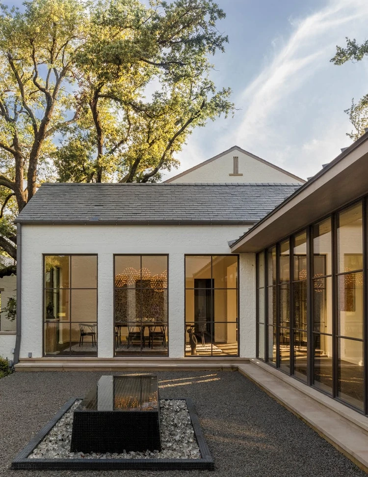 A white courtyard with black window trim and dark pea gravel patio.