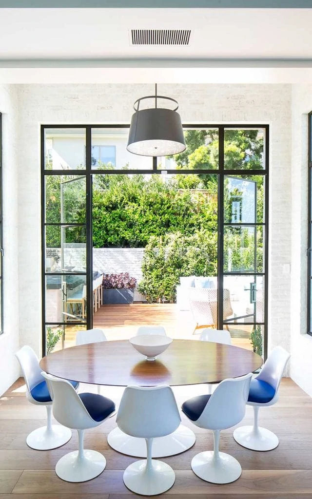 Black framed windows and door lead from this kitchen nook to an outdoor entertaining area.