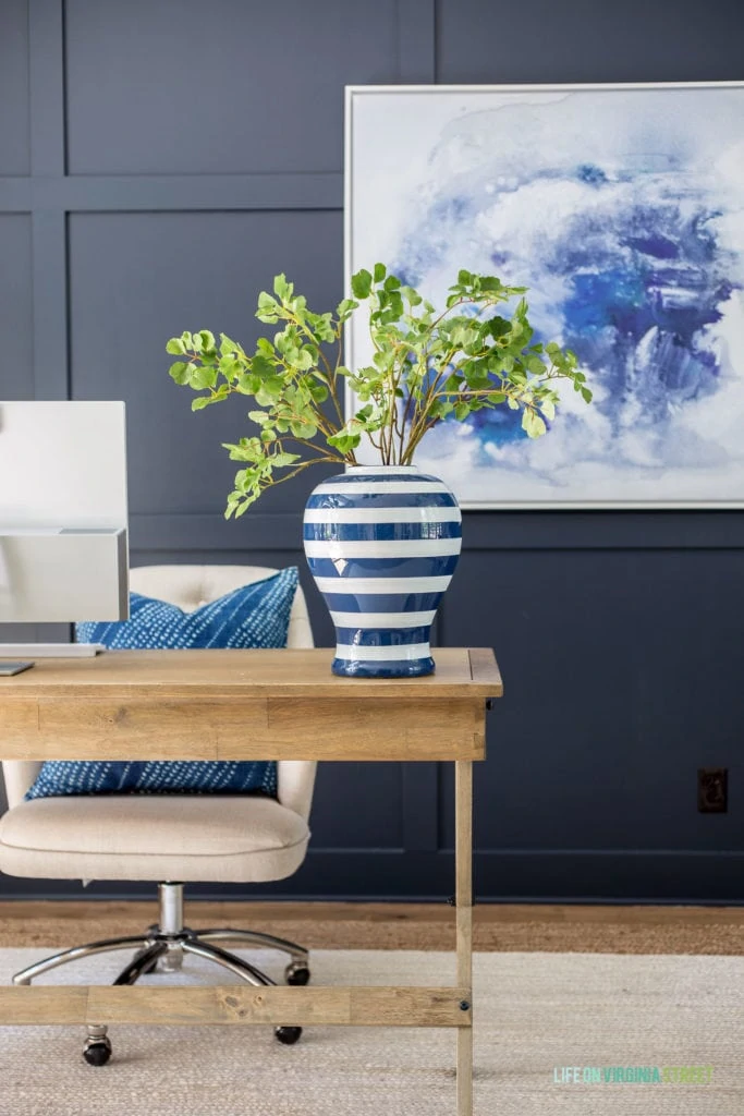 Faux ginkgo stems in a blue and white striped vase in a home office.