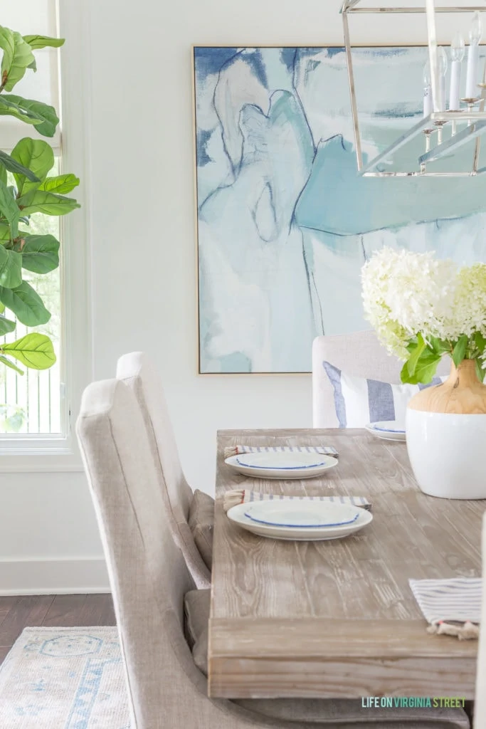 The wooden table in the dining room and an abstract picture at the head of the table on the wall.