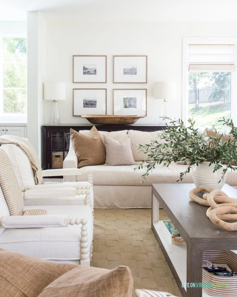 A wood gallery wall with black and white photos in a neutral living room decorated for fall.