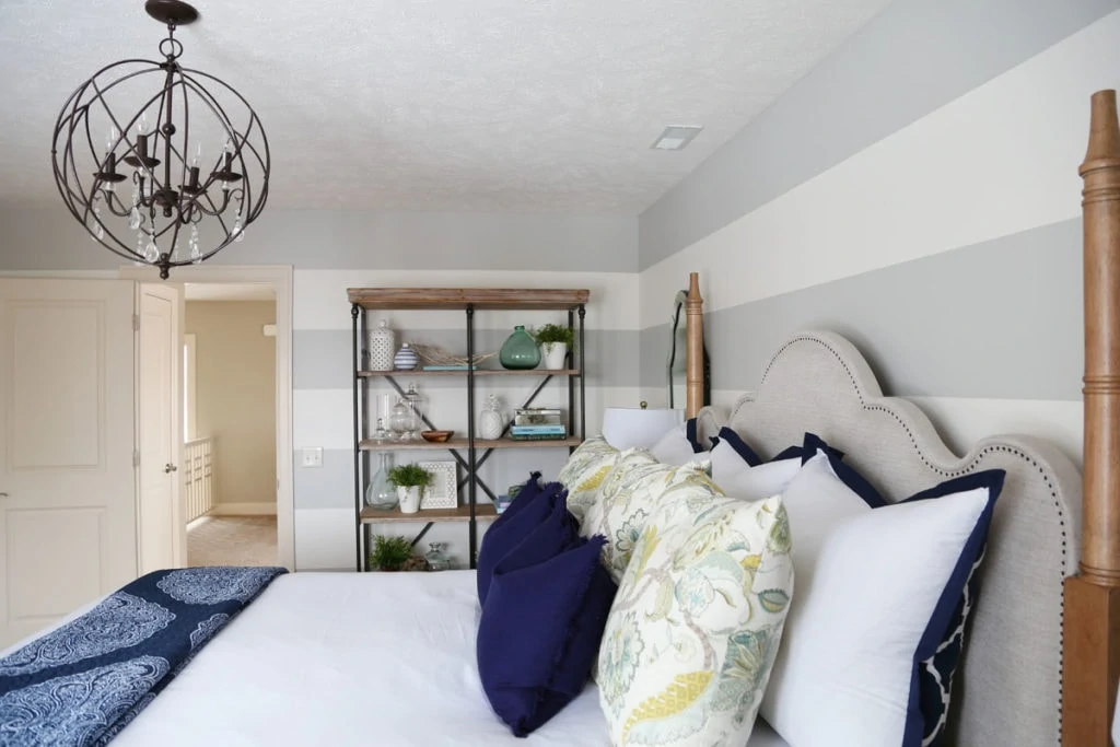 An orb chandelier above the bed in the guest bedroom, with open shelving beside the bed.
