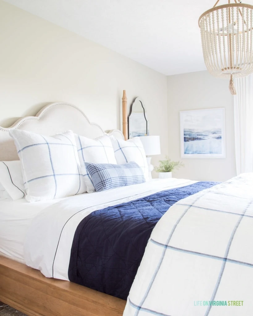 A blue sateen blanket on the bed with blue and white striped pillows.