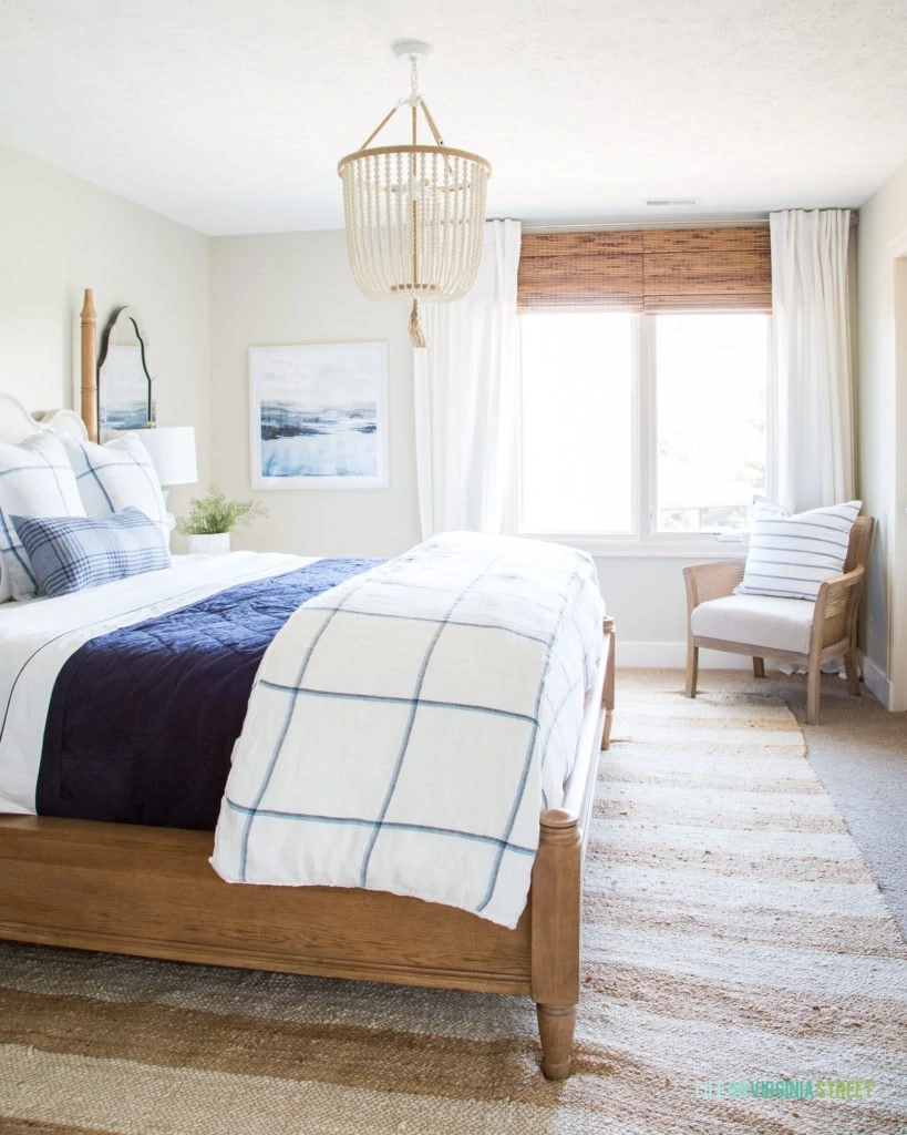 A bedroom with a blue and white bedding, and a beaded chandelier.