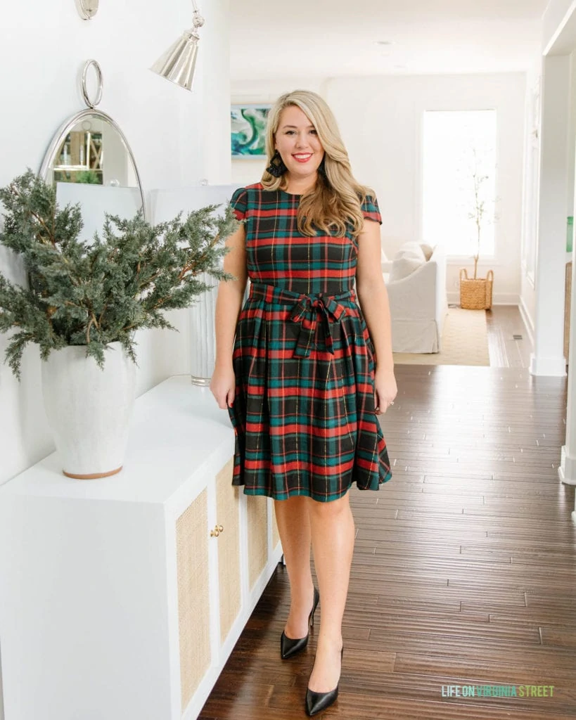 Sarah in a plaid dress in the hallway beside a hallway table.