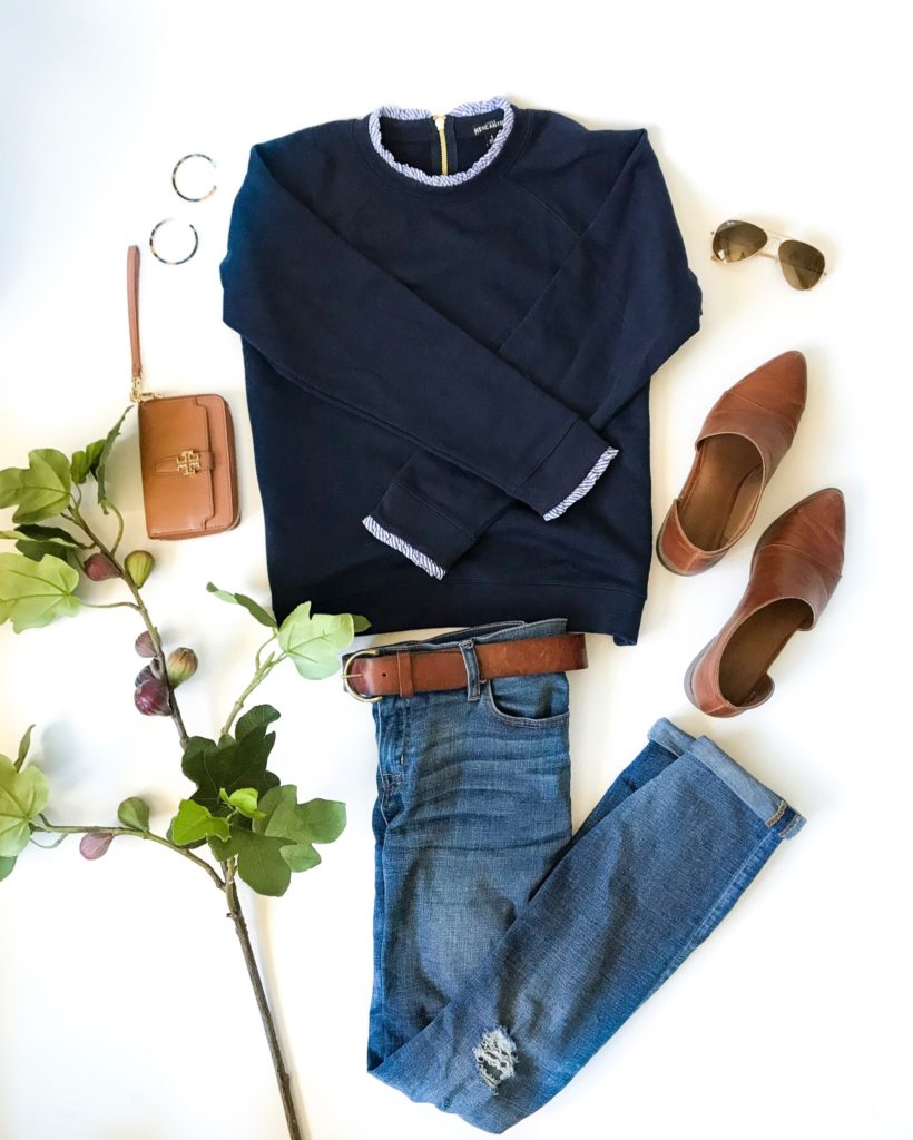 A dressy sweatshirt in navy blue, jeans and flat brown shoes.