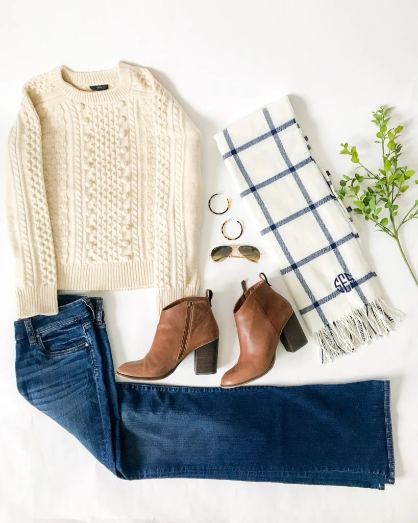 A windowpane scarf, brown booties, and a neutral sweater with jeans.