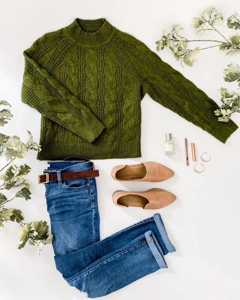 Mockneck green cableknit sweater, jeans with a belt and neutral shoes.