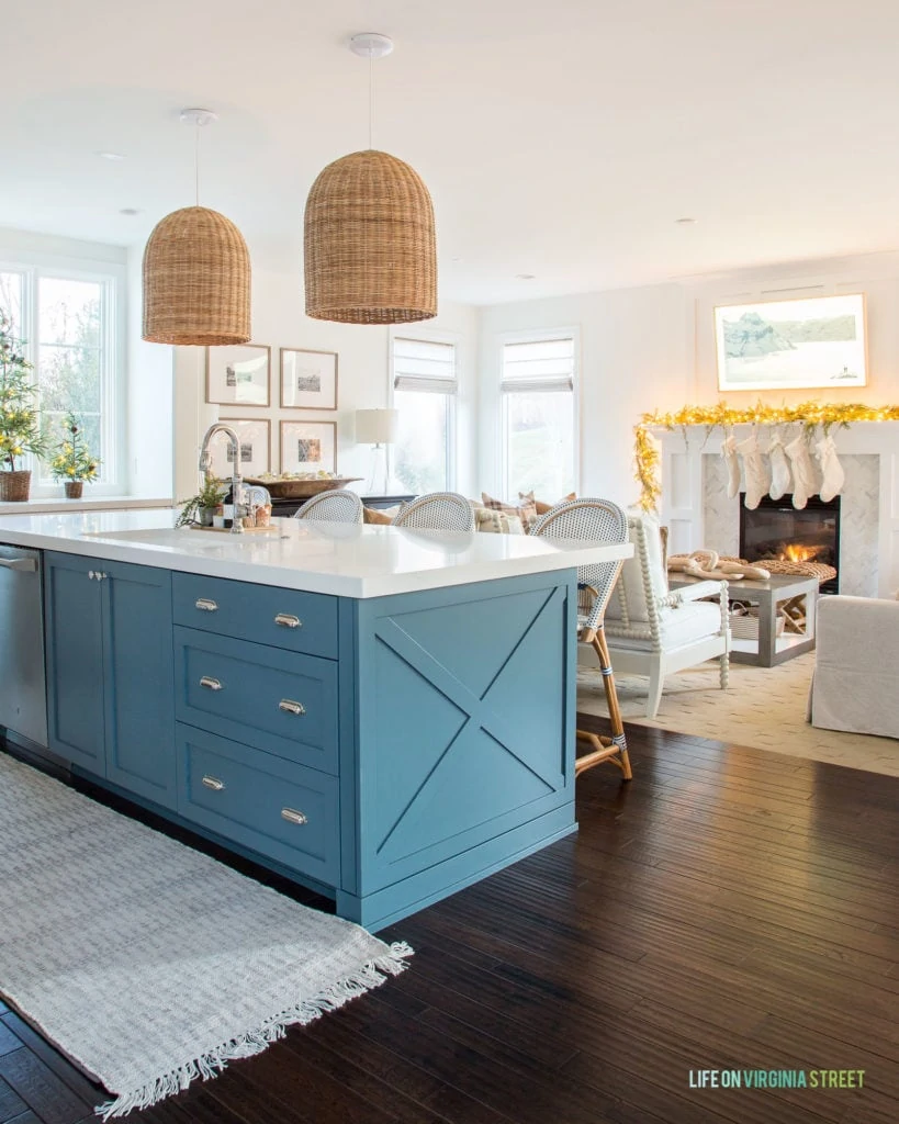 Christmas kitchen with blue island and stocking hung over the fireplace.