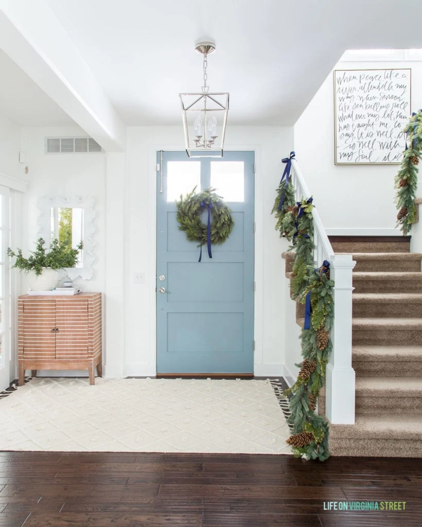 Blue Christmas decor in a coastal inspired entryway! I love the garland on the staircase and the 'It Is Well' handwritten art!