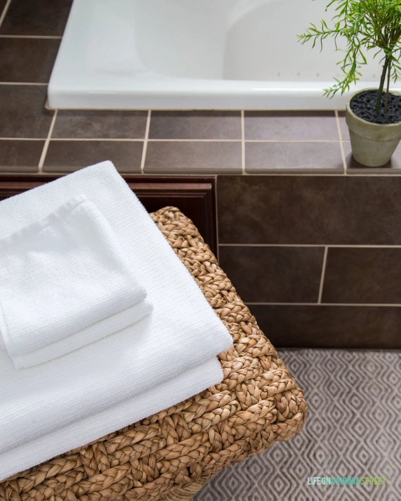 A small stool beside the tub with white towels on it.