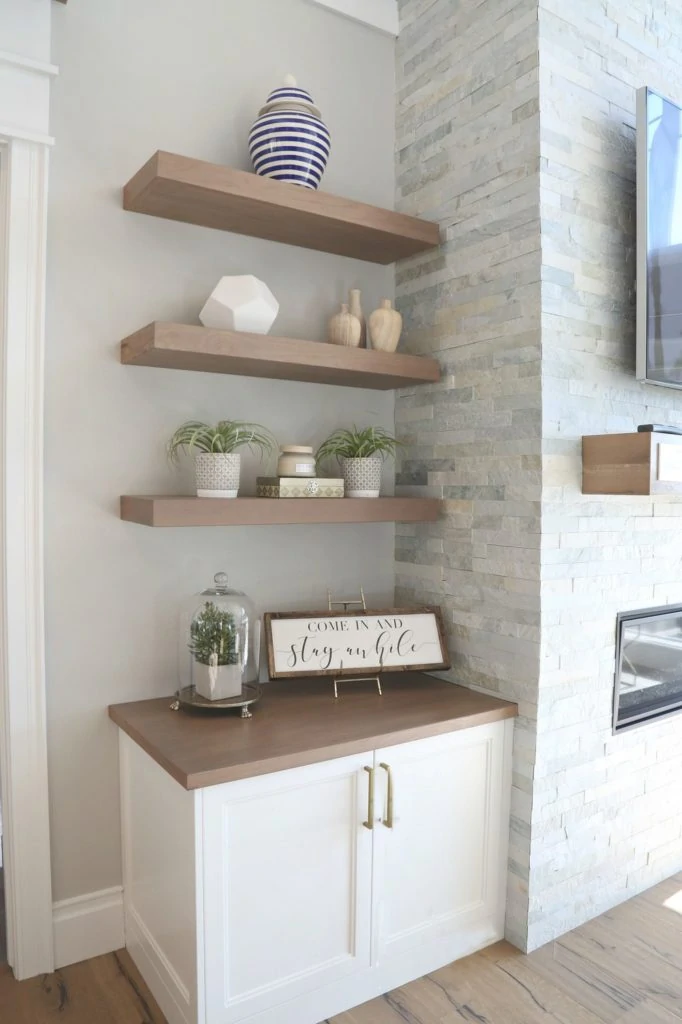 The best gray paint colors! Benjamin Moore Gray Owl Living Room with floating wood shelves and a stacked stone fireplace.