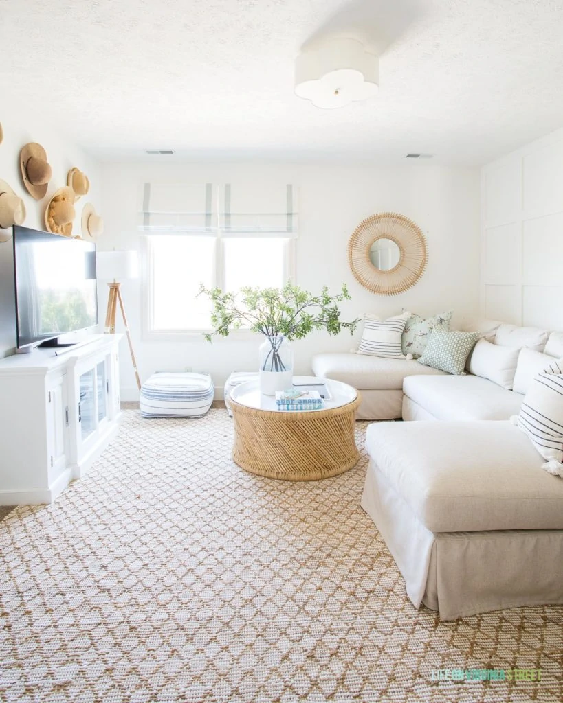 A coastal inspired den with a linen sectional, Benjamin Moore Simply White walls, and cane and rattan accents.