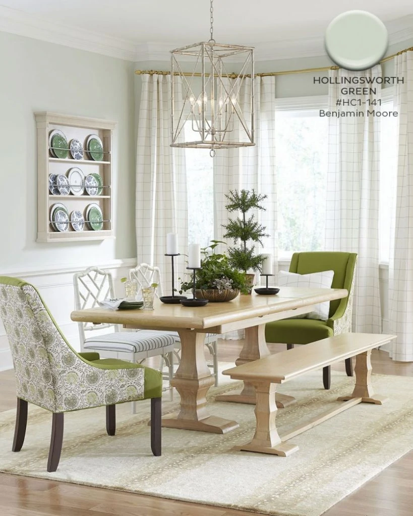 Benjamin Moore Hollingsworth Green painted walls in a dining room with a pendant chandelier and light wood trestle table.