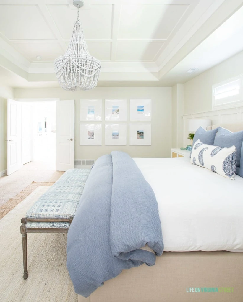 A gallery wall hanging in a coastal bedroom with oversized white frames and mats featuring beach photography as artwork.