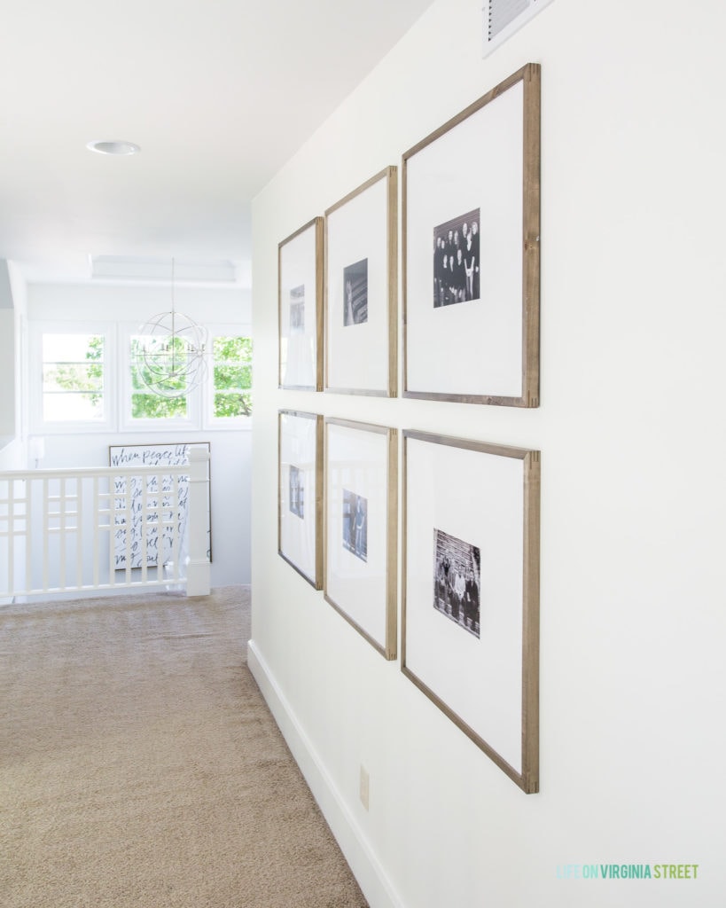 An oversized photo gallery wall in a long hallway leading to a staircase.