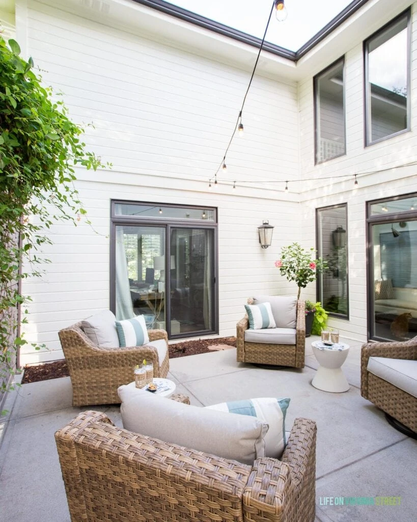 A courtyard patio space surrounded by a white painted house with black window trim.