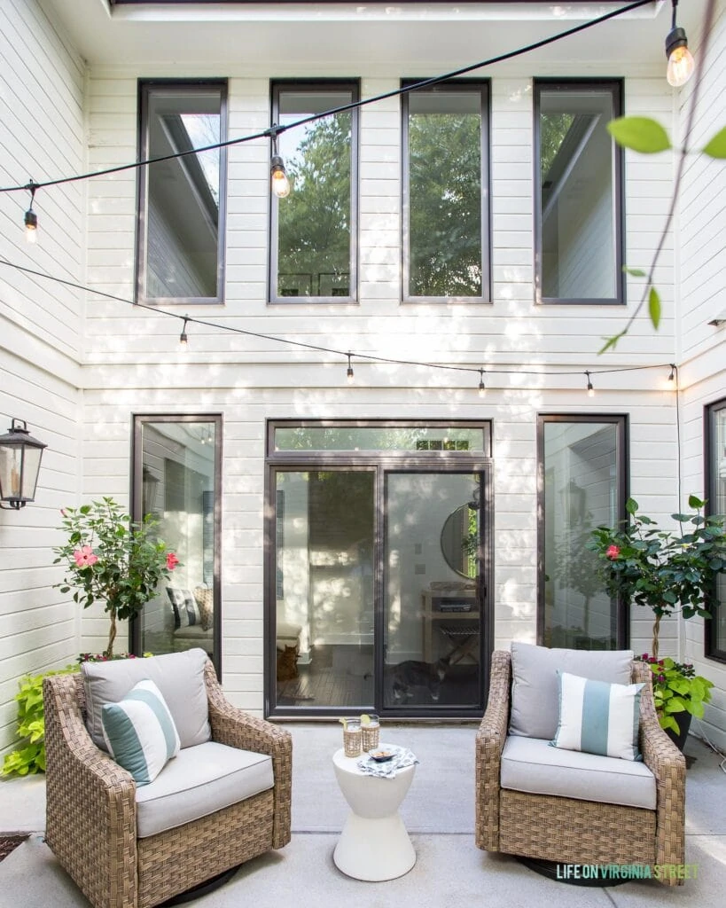 A white house with black window frames surrounding an outdoor courtyard area.