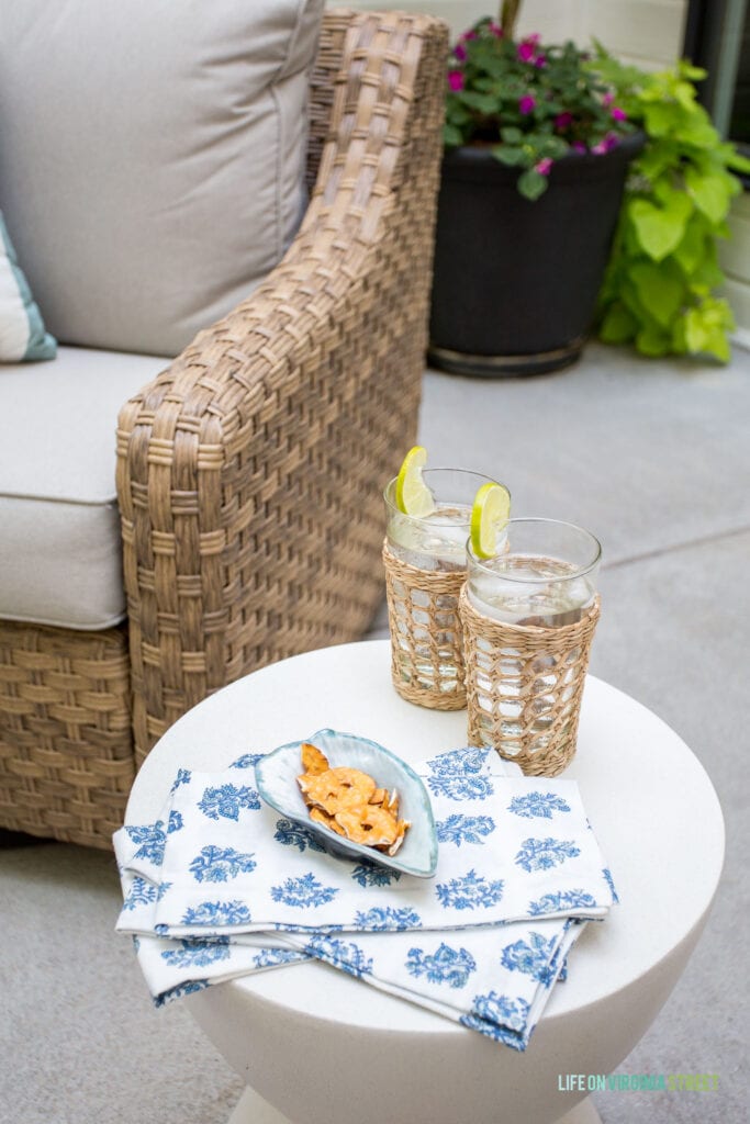 Cute blue and white block print napkins, cane drinking glasses, and a white concrete side table in an outdoor patio spot.