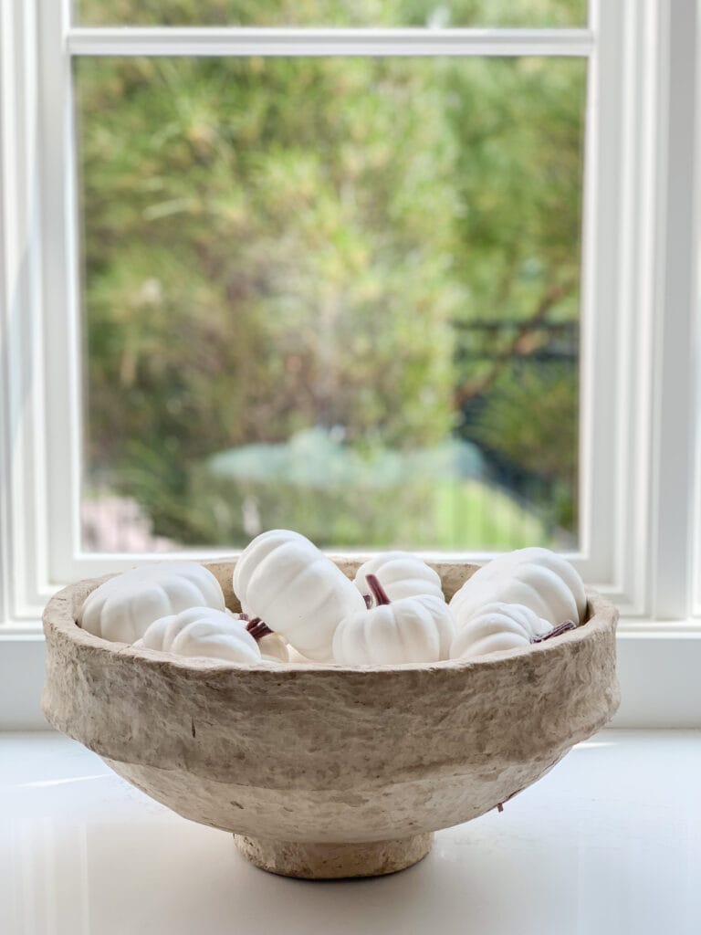 A paper mache bowl filled with mini white faux pumpkins as part of this 2020 fall home tour.