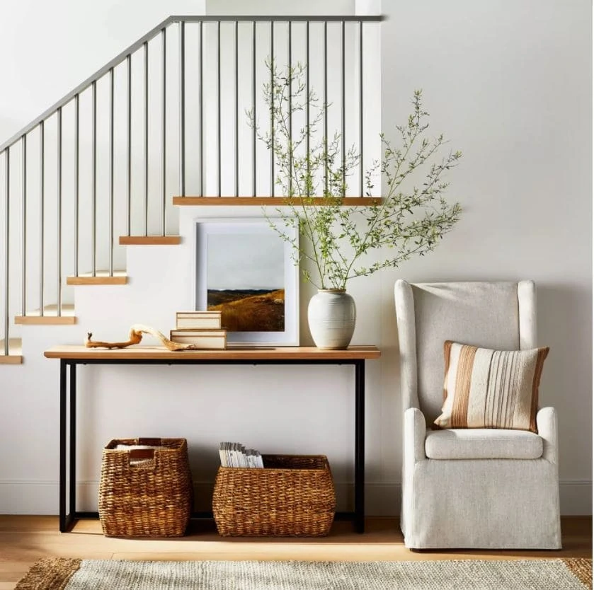 An entryway decorated for fall with a wood and iron console table, upholstered armchair, ceramic vase, woven baskets, landscape art, and ceramic vase with large branches. All from the new Studio McGee fall collection at Target!
