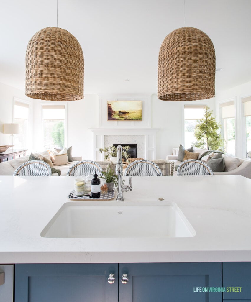 View from a kitchen island with rattan pendant lights into a living room with a Frame TV.