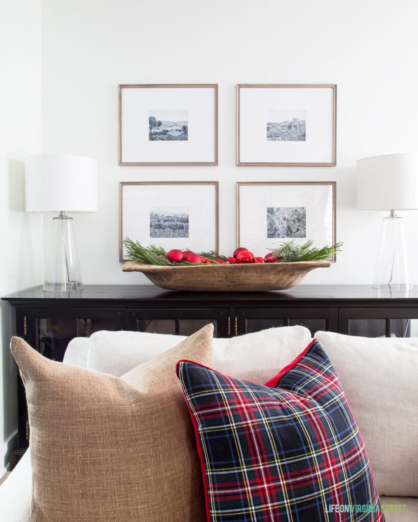 Christmas pillows with traditional plaid and bronze linen. Also includes a gallery wall behind a large wood dough bowl filled with ornaments and greenery.