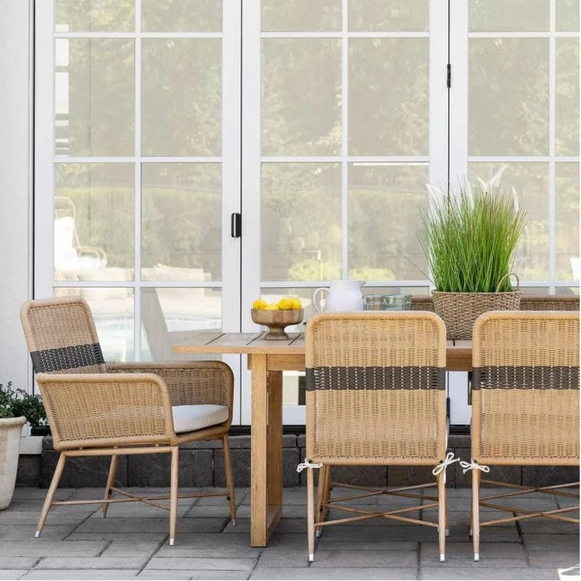 Outdoor dining with striped outdoor wicker chairs, an outdoor wood dining table, and outdoor place settings from the Studio McGee Threshold Patio Collection.