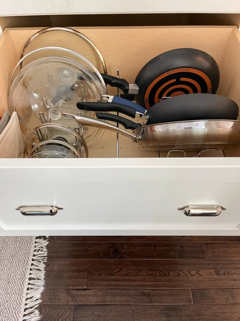 A kitchen drawer that stores cooking pans and lids.