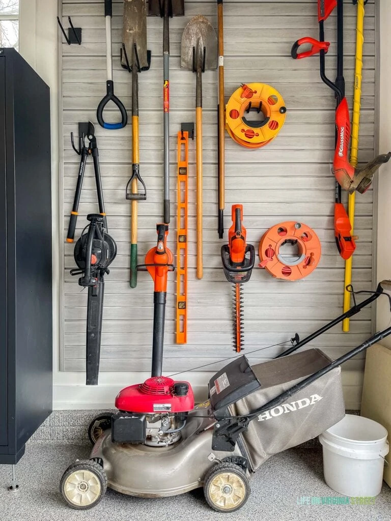 Gardening tools stored on a garage slat wall to keep the garage organized.