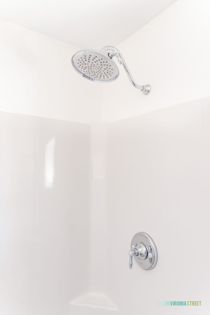 A large chrome shower head in a shower insert stall.