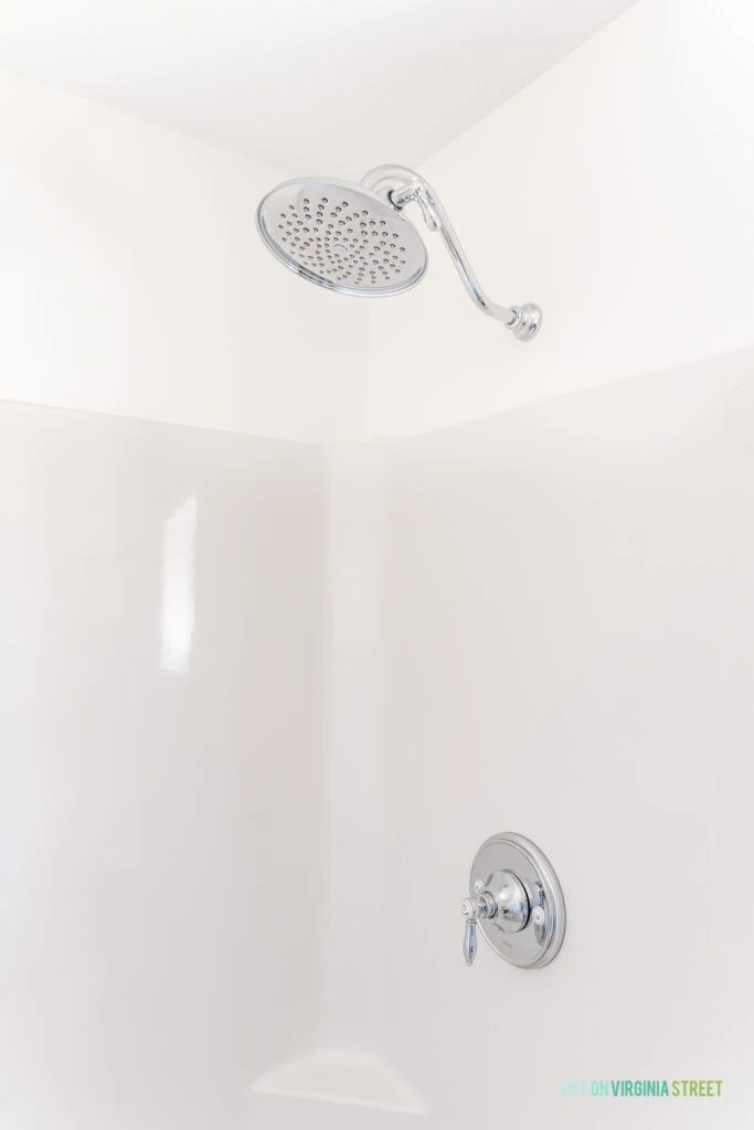 A large chrome shower head in a shower insert stall.