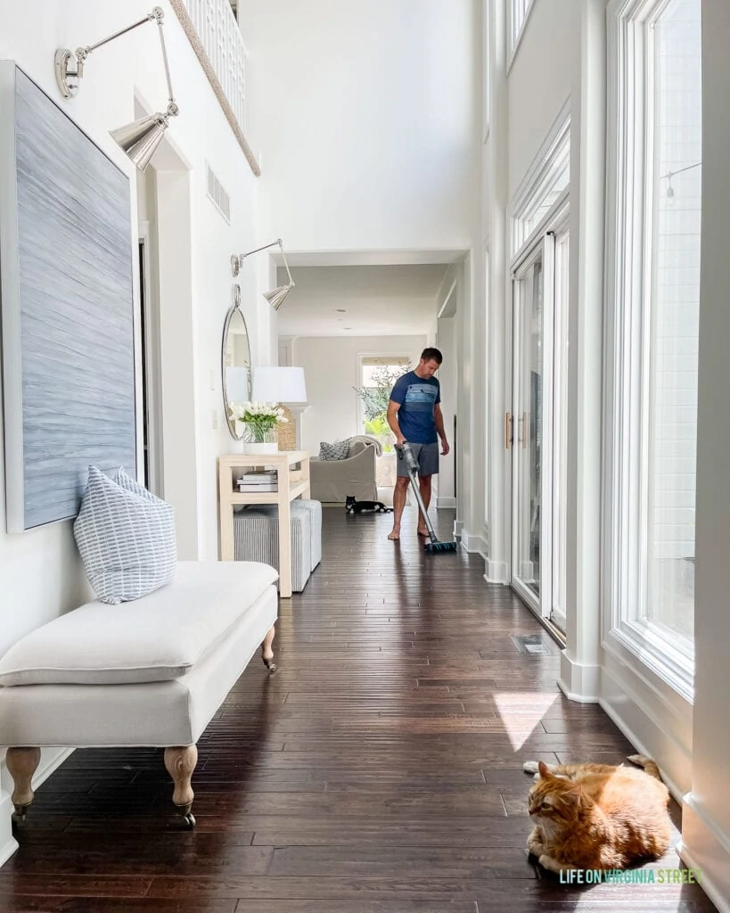 A Samsung Jet 75 Review, shown in use in a long hallway with dark hardwood floors and cats.