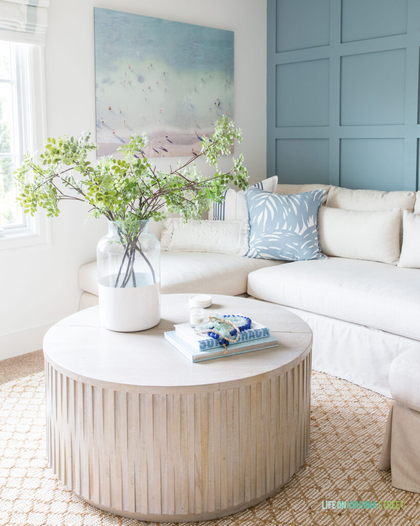 Sharing my favorite traditional coastal coffee tables like this gray washed fluted coffee table decorated in a blue and white den with beach art. Includes many more styles and options.