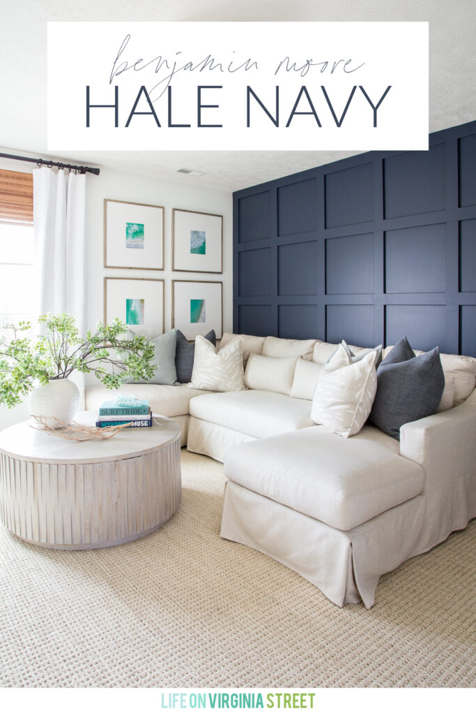 A color spotlight on Benjamin Moore Hale Navy, shown here in our cozy den with a linen sectional, round coffee table, and gallery wall art.