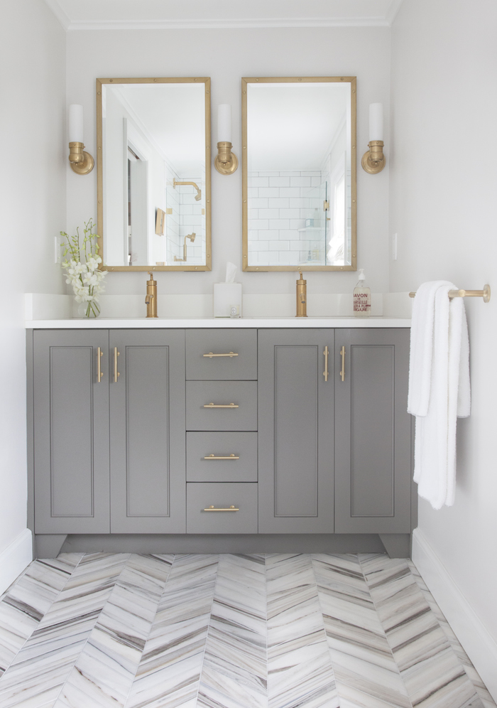 designer Erin Gates paired her Benjamin Moore Chelsea Gray bathroom cabinets with Sherwin Williams Eider White on the walls and warm brass hardware.