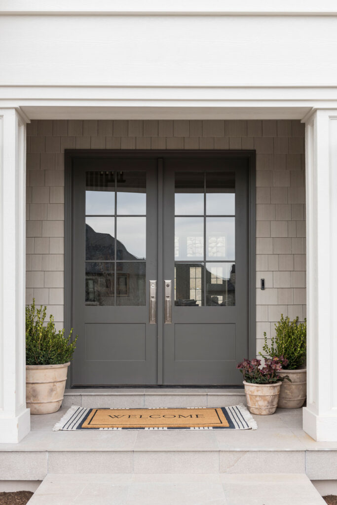The best gray paint colors, as demonstrated on a shake shingle house porch with Benjamin Moore Kendall Charcoal front doors.