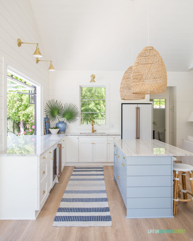 A coastal style poolhouse kitchen featuring White Macaubus Quartzite countertops. Discussing the pros and cons of quartzite along with other types of kitchen countertops.