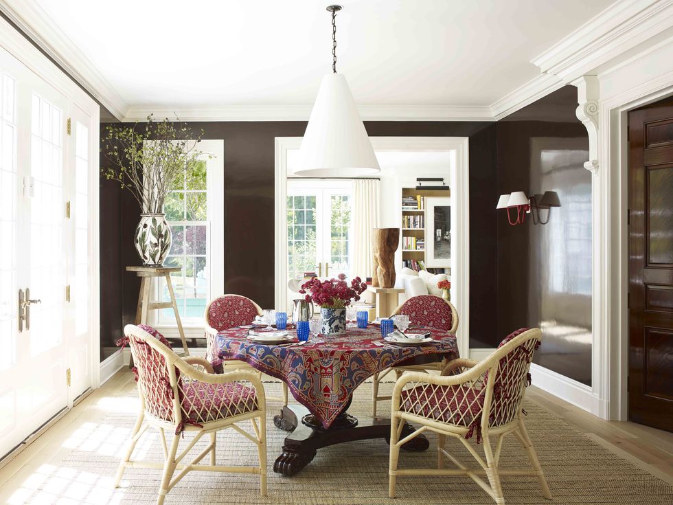 A dining room featuring glossy brown walls painted Farrow & Ball's Tanner's Brown, one of the best brown paint colors!