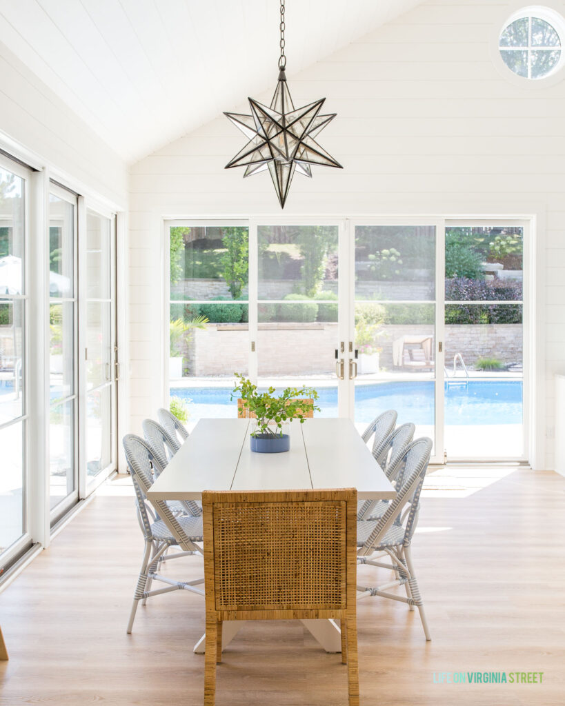 Modern coastal cottage dining chairs in a pool house dining room with white shiplap walls, a moravian star chandelier, and light LVP floors.