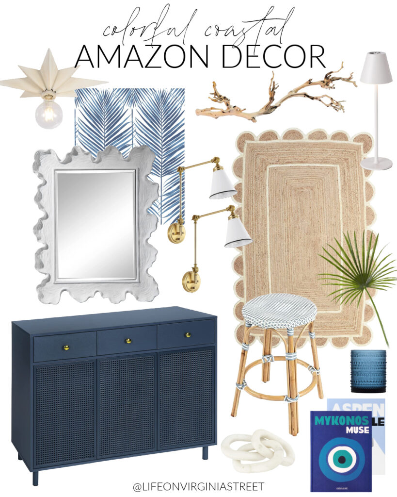 Colorful coastal Amazon decor that includes a navy blue rattan cabinet, white scalloped mirror, blue palm print peel and stick wallpaper, a white star light fixture, scalloped jute rug, faux fan palm stem, woven counter stool, and colorful coffee table books.