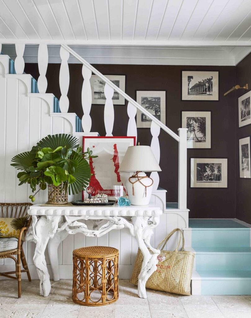 A coastal staircase with white railing, dark brown walls, and aqua painted stair treads.