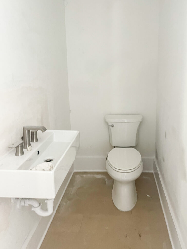 A small powder bathroom under construction with a tiny sink mounted to the wall.