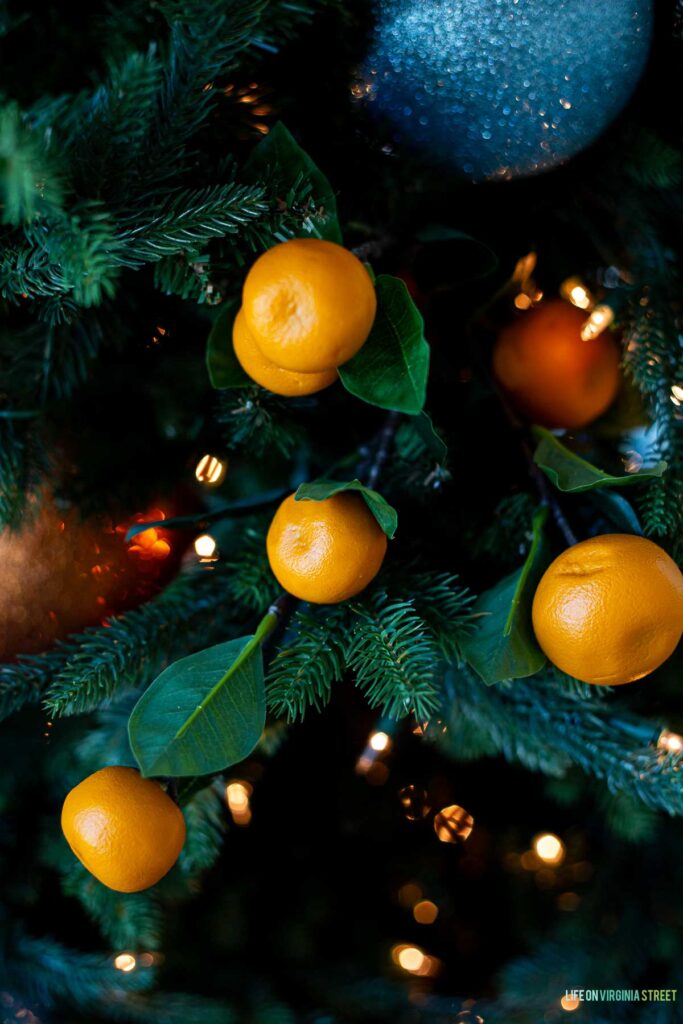 Artificial oranges on a Christmas tree with blue and orange ornaments.