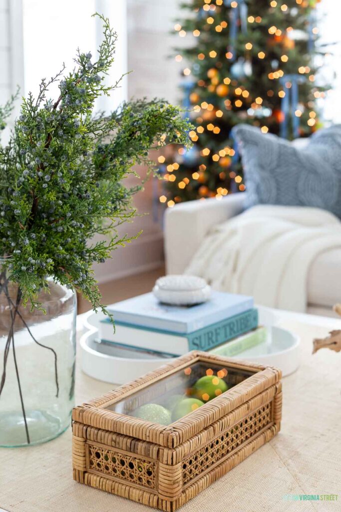 A rattan cane box filled with green ornaments in a coastal Christmas home tour.
