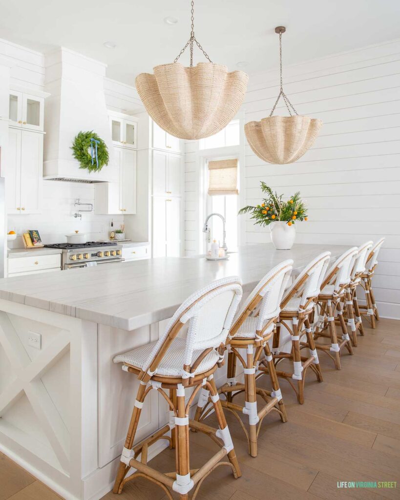 Palecek Isla Chandelier hanging in a coastal Christmas kitchen with white Serena & Lily counter stools, evergreen accents, and white shiplap walls.