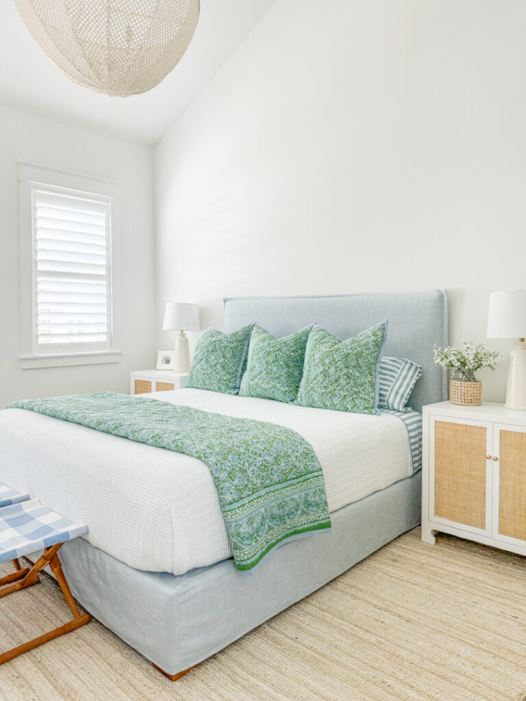 Simple bedroom updates to freshen up your spaces! This room includes a blue linen bed from Serena & Lily, a blue and green quilt, blue and white striped sheets, rattan nightstands, a jute rug and a large bead chandelier.